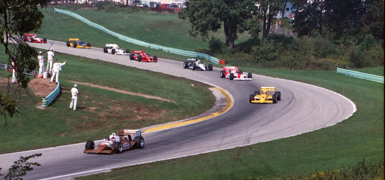 A slew of classic race cars thunder down the race track